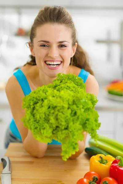 Ευτυχισμένη νέα γυναίκα που κρατά την πράσινη σαλάτα στην κουζίνα — Φωτογραφία Αρχείου