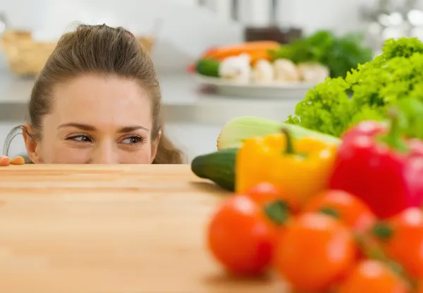 Młoda kobieta, patrząc od deski do krojenia i patrząc na vegeta — Zdjęcie stockowe