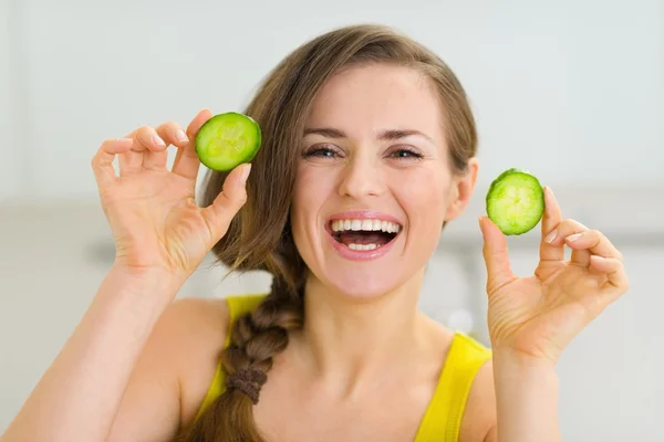 Lachende jonge vrouw met plakjes komkommer — Stockfoto