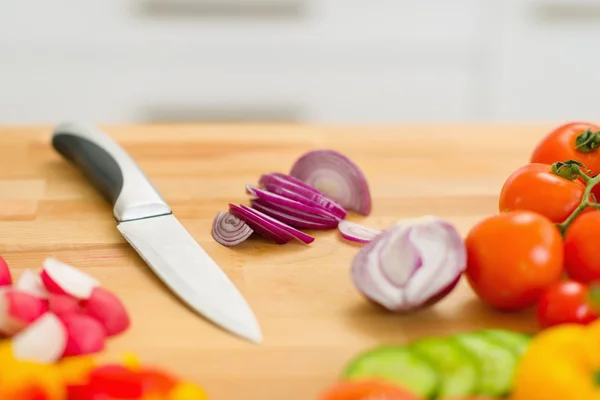Primo piano su fette di cipolla e coltelli sul tagliere — Foto Stock