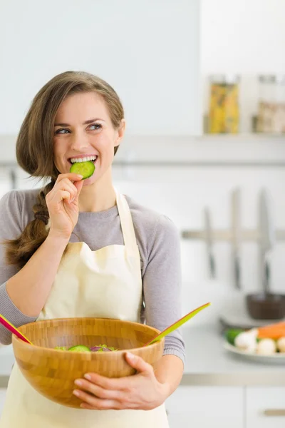 Feliz joven ama de casa degustación rebanada de pepino de verduras s — Foto de Stock