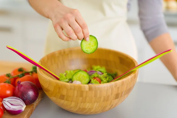 Крупный план домохозяйки, добавляющей огурец в овощной салат — стоковое фото