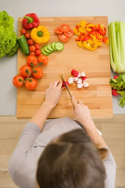 Vrouw snijden van groenten op snijplank — Stockfoto