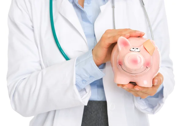 Closeup on medical doctor woman holding piggy bank with patch on — Stock Photo, Image