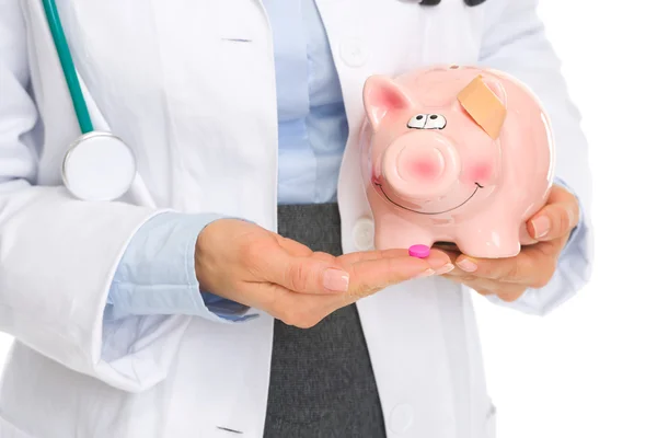 Close-up op arts vrouw pillen geven piggy bank — Stockfoto