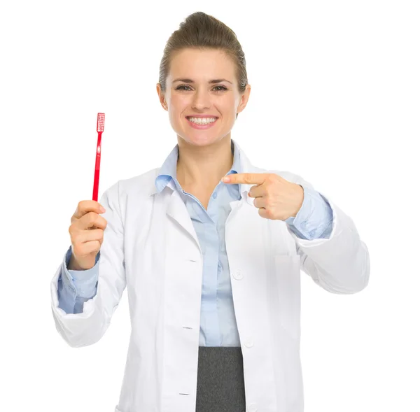 Sorridente medico dentale donna che punta spazzolino da denti — Foto Stock