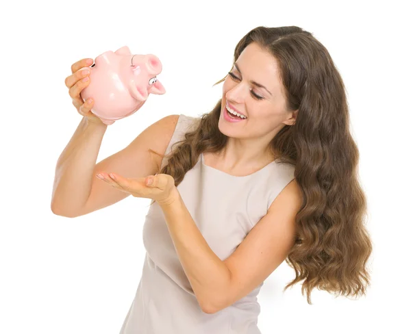 Happy young woman shaking out coins from piggy bank — Stock Photo, Image