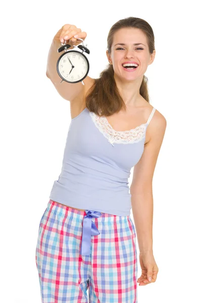 Happy young woman in pajamas showing alarm clock — Stock Photo, Image