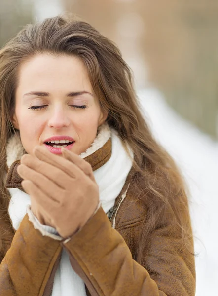 Mujer joven calentando las manos en invierno al aire libre — Foto de Stock