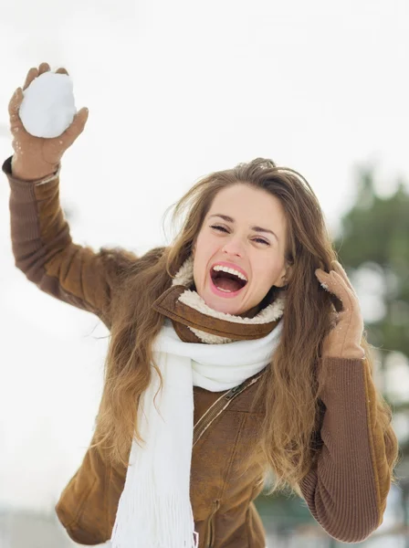 Felice giovane donna lanciando palla di neve nel parco invernale — Foto Stock