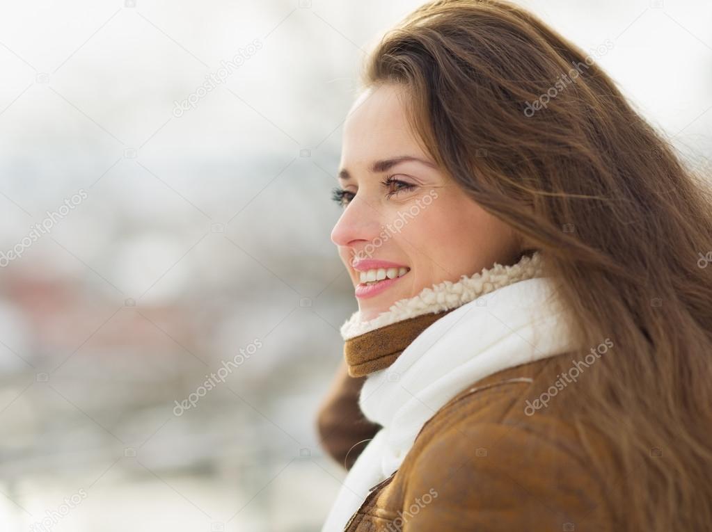 Portrait of happy young woman looking on copy space in winter ou
