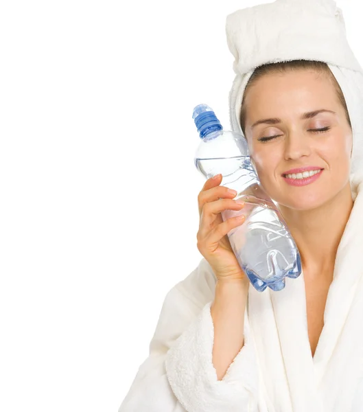 Junge Frau im Bademantel hält Flasche mit Wasser in der Hand — Stockfoto