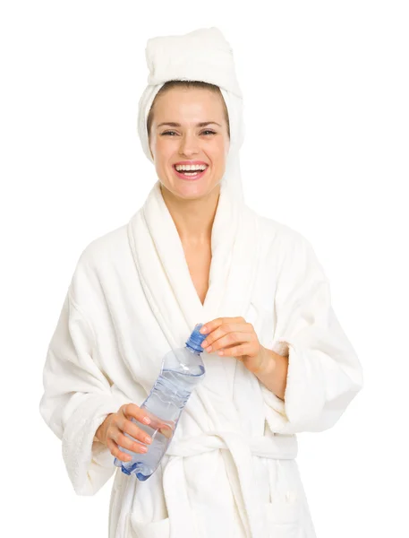 Mujer joven sonriente en bata de baño sosteniendo la botella con agua — Foto de Stock