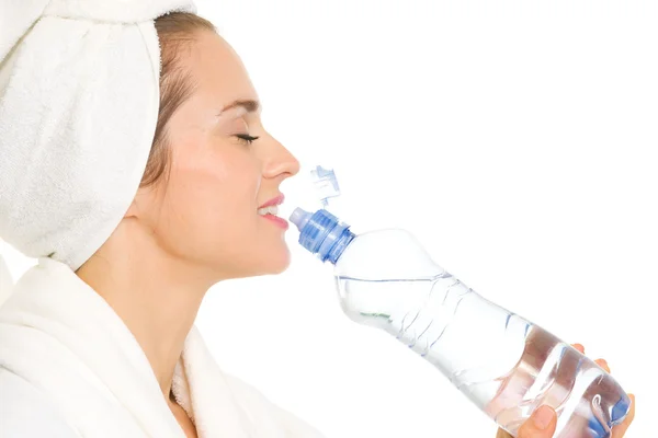 Jonge vrouw in badjas drinkend uit de fles met water — Stockfoto