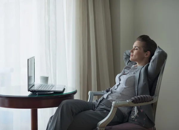 Relaxado mulher de negócios sentado na cadeira no quarto de hotel — Fotografia de Stock