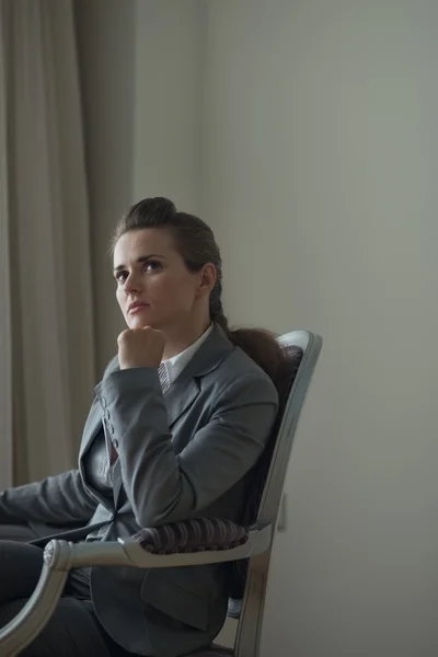 Thoughtful business woman sitting in chair in hotel room — Stock Photo, Image