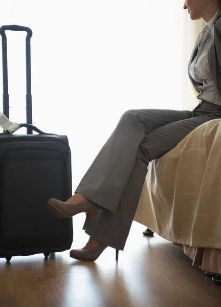 Tired business woman sitting on bed in hotel room after trip — Stock Photo, Image