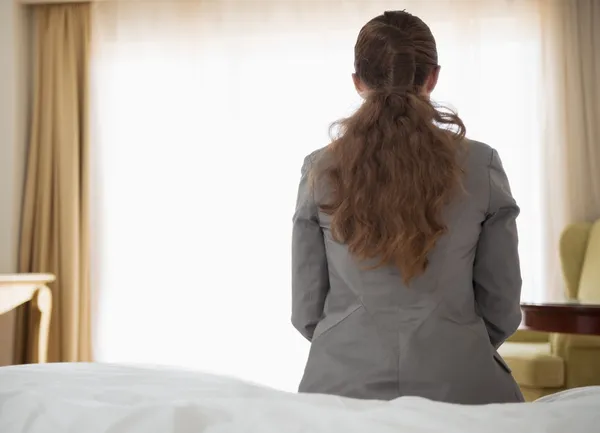 Mulher de negócios sentada na cama no quarto de hotel. vista traseira — Fotografia de Stock