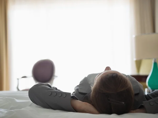 Mujer de negocios acostada en la cama en la habitación del hotel. visión trasera — Foto de Stock