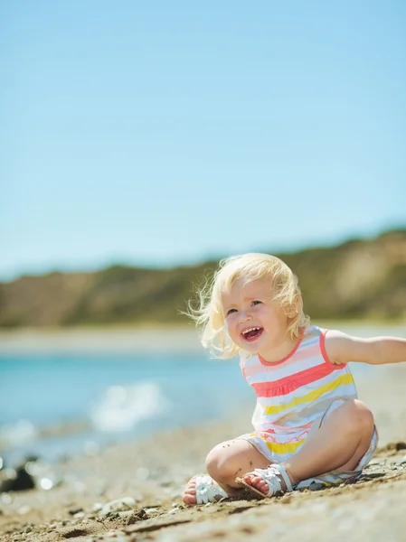 Счастливая девочка играет с песком на пляже — стоковое фото