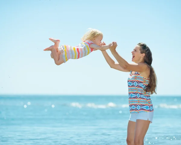 Happy mother and baby girl playing at seaside — Stock Photo, Image