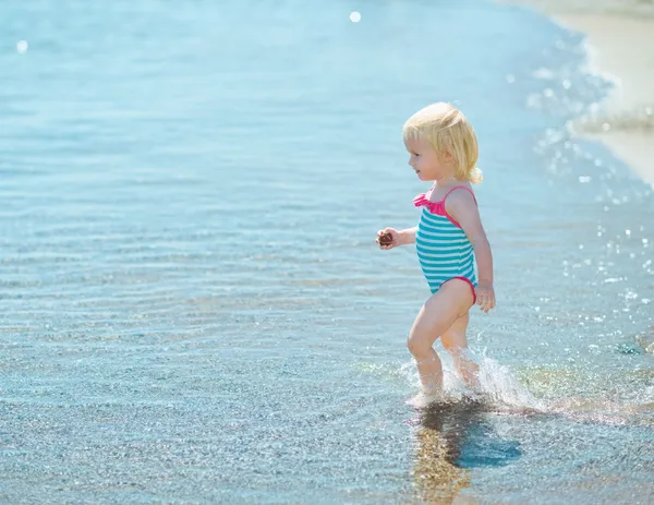 Meisje van de baby wandelen in zee — Stockfoto