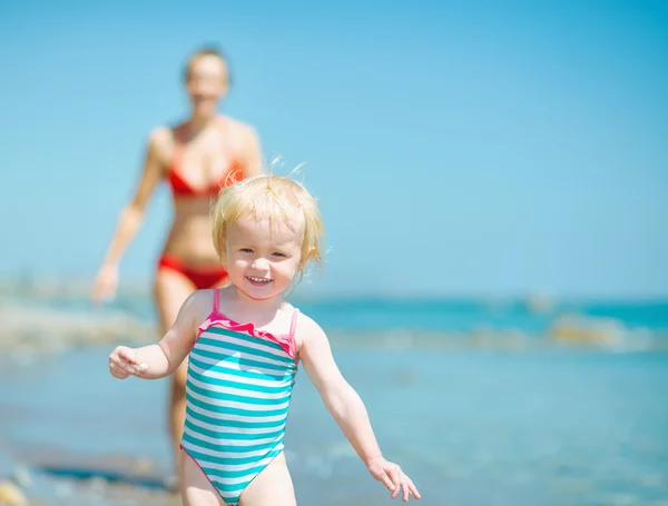 Matka a dítě dívka hrající na břehu moře — Stock fotografie