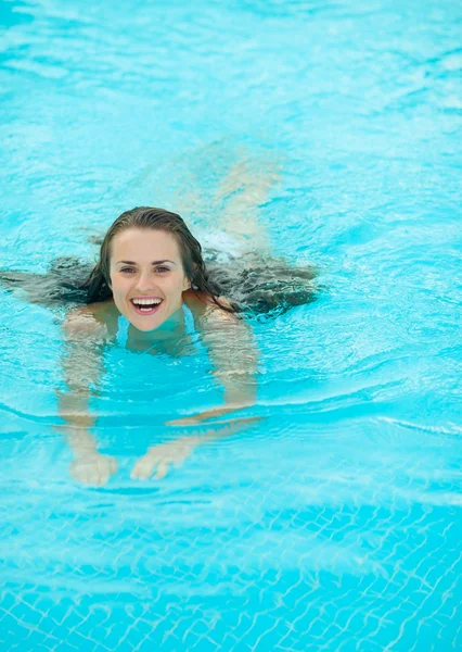 Heureuse jeune femme nageant dans la piscine — Photo