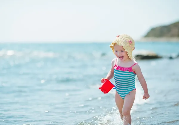 Счастливого малыша, бегущего вдоль берега моря — стоковое фото
