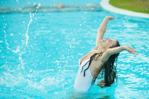 Happy young woman splashing water in pool — Stock Photo, Image