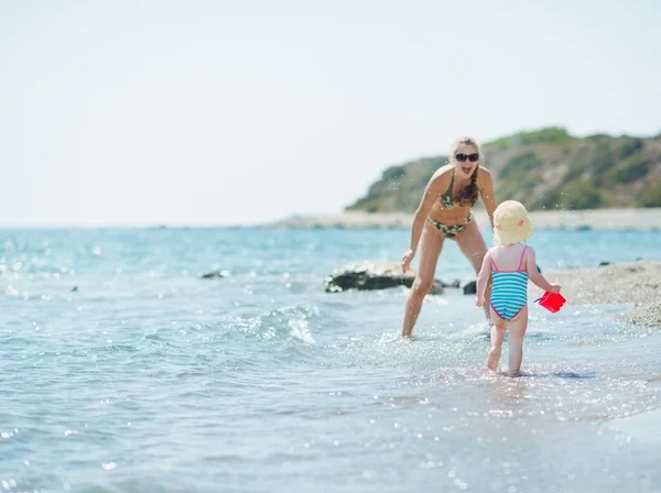 Happy mother and baby girl playing at seaside — Stock Photo, Image