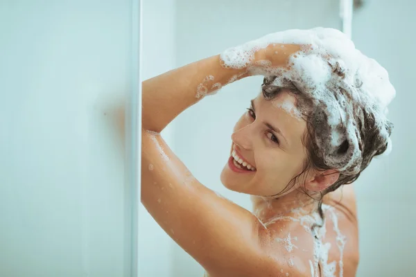 Smiling young woman washing head with shampoo — Stock Photo, Image