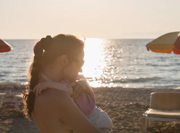 Силуэт матери, обнимающей ребенка на одиноком пляже — стоковое фото