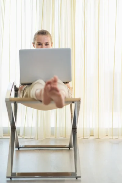 Junge Frau sitzt auf modernem Stuhl und benutzt Laptop — Stockfoto
