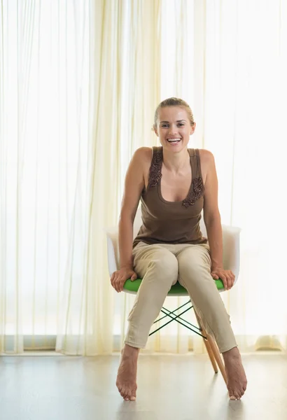 Улыбающаяся молодая женщина сидит на современном стуле — стоковое фото