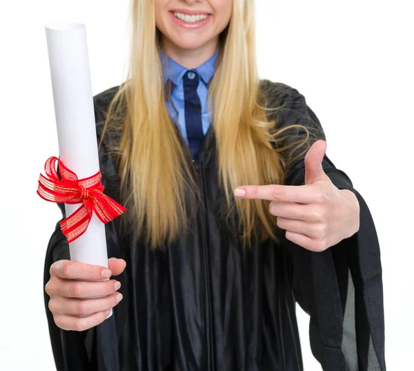 Gros plan sur la femme en robe de fin d'études pointant sur le diplôme — Photo