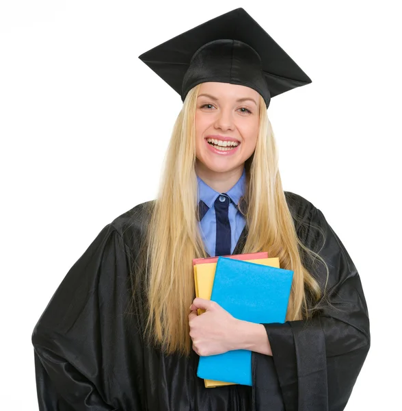 Glimlachend jonge vrouw in afstuderen jurk met boeken — Stockfoto