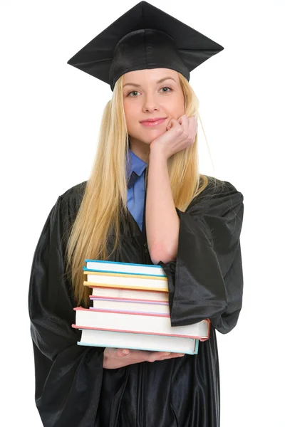 Gelukkig jonge vrouw in afstuderen jurk met boeken — Stockfoto