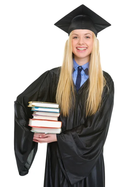 Retrato de una joven sonriente en vestido de graduación sosteniendo libros — Foto de Stock