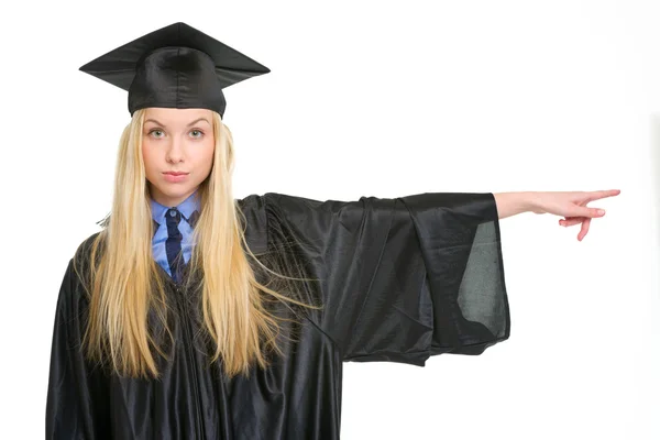 Jovem mulher em vestido de graduação apontando no espaço cópia — Fotografia de Stock