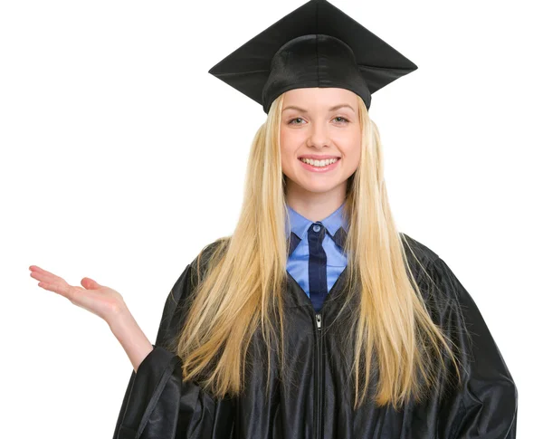 Sorrindo jovem mulher em vestido de graduação apontando no espaço cópia — Fotografia de Stock