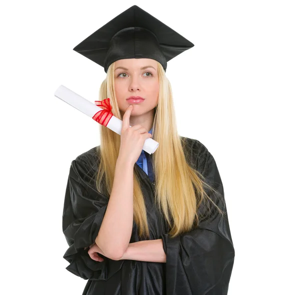 Doordachte jonge vrouw in afstuderen jurk met diploma — Stockfoto