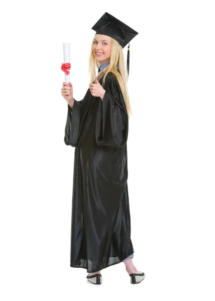 Full length portrait of young woman in graduation gown showing d — Stock Photo, Image