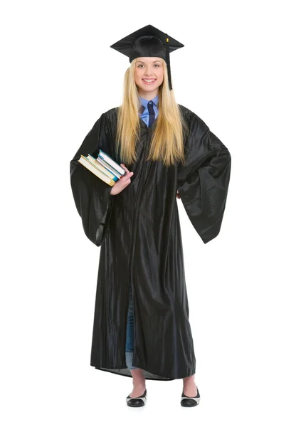 Full length portrait of young woman in graduation gown with book — Stock Photo, Image