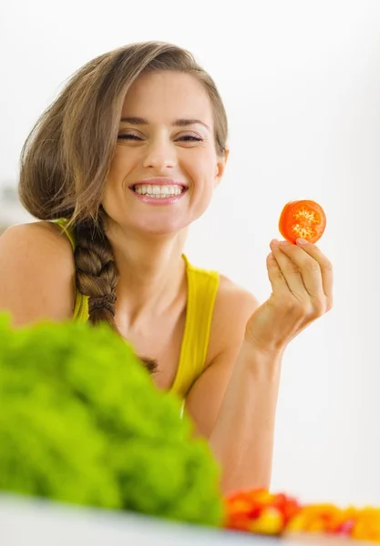 Portret van gelukkige jonge vrouw met tomaat in keuken — Stockfoto