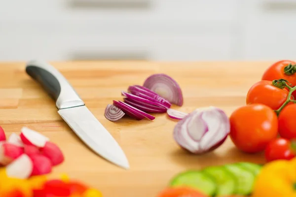 Primo piano su cipolla e coltello sul tagliere — Foto Stock