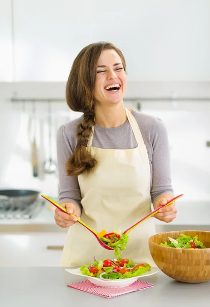 Sorrindo jovem servindo salada fresca no prato — Fotografia de Stock