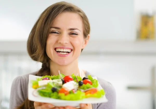 Sorrindo jovem mulher mostrando salada fresca — Fotografia de Stock