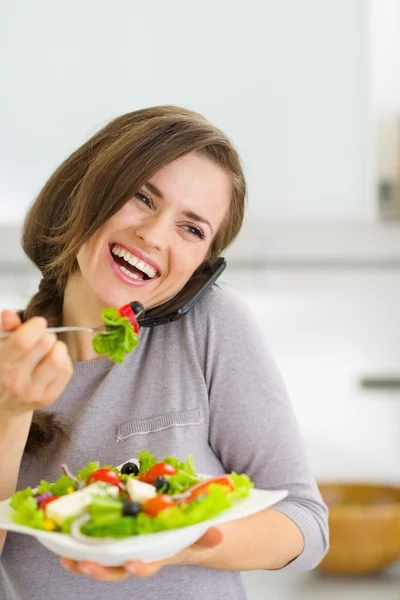 Lächelnde junge Frau isst Salat und telefoniert mit dem Handy — Stockfoto