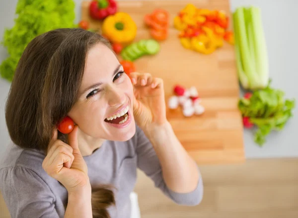 Jonge vrouw met behulp van cherry tomaten als earring glimlachen — Stockfoto